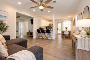 A modern living room with a sofa, ottoman, and a ceiling fan. - Bay Esplanade By GoldenCoastRentals (Clearwater)
