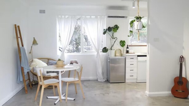 Ein modernes, helles Zimmer mit Essbereich, einer kleinen Küche und einer Gitarre.