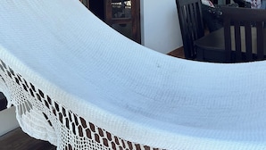 Eine Hängematte in einem Zimmer mit Holztüren, einem Tisch und Stühlen.