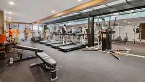 Uma academia moderna com esteiras, aparelhos de musculação e um banco.