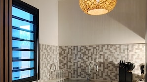 Une cuisine au design moderne, avec un dosseret à motifs géométriques, un évier en acier inoxydable et un luminaire suspendu.
