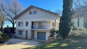 Ein zweigeschossiges Haus mit einer Stein-Fassade, einem Balkon und einer Garage.