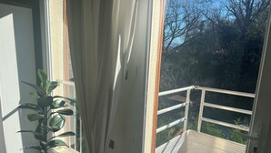 Ein Balkon mit Metallgeländer, einem Blumentopf und einem Teddybären-Anhängers.