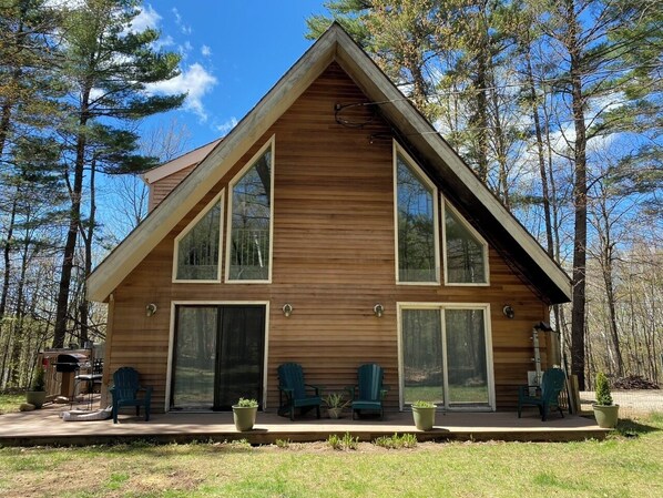 Une cabane en bois dotée d’un grand porche à l’avant, de deux grandes fenêtres et d’un toit en pente.