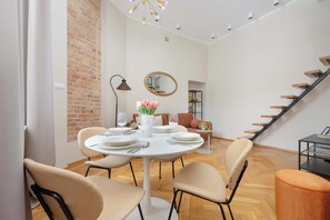 Ein moderner Essbereich mit einem runden Tisch, Stühlen und einer Blumenvase. Im Hintergrund ist eine Treppe zu sehen.