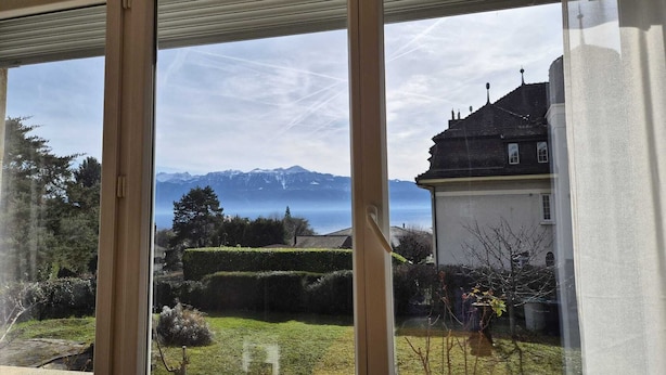 Vista a través de una ventana que muestra una cordillera y una masa de agua.
