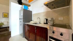 Uma cozinha compacta com geladeira, cafeteira e fogão.