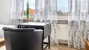 Una habitación con cama, escritorio y ventana con cortinas florales.