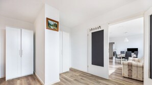 Un interior moderno con suelo de madera, paredes blancas, una zona de comedor con mesa y sillas, y un sofá.
