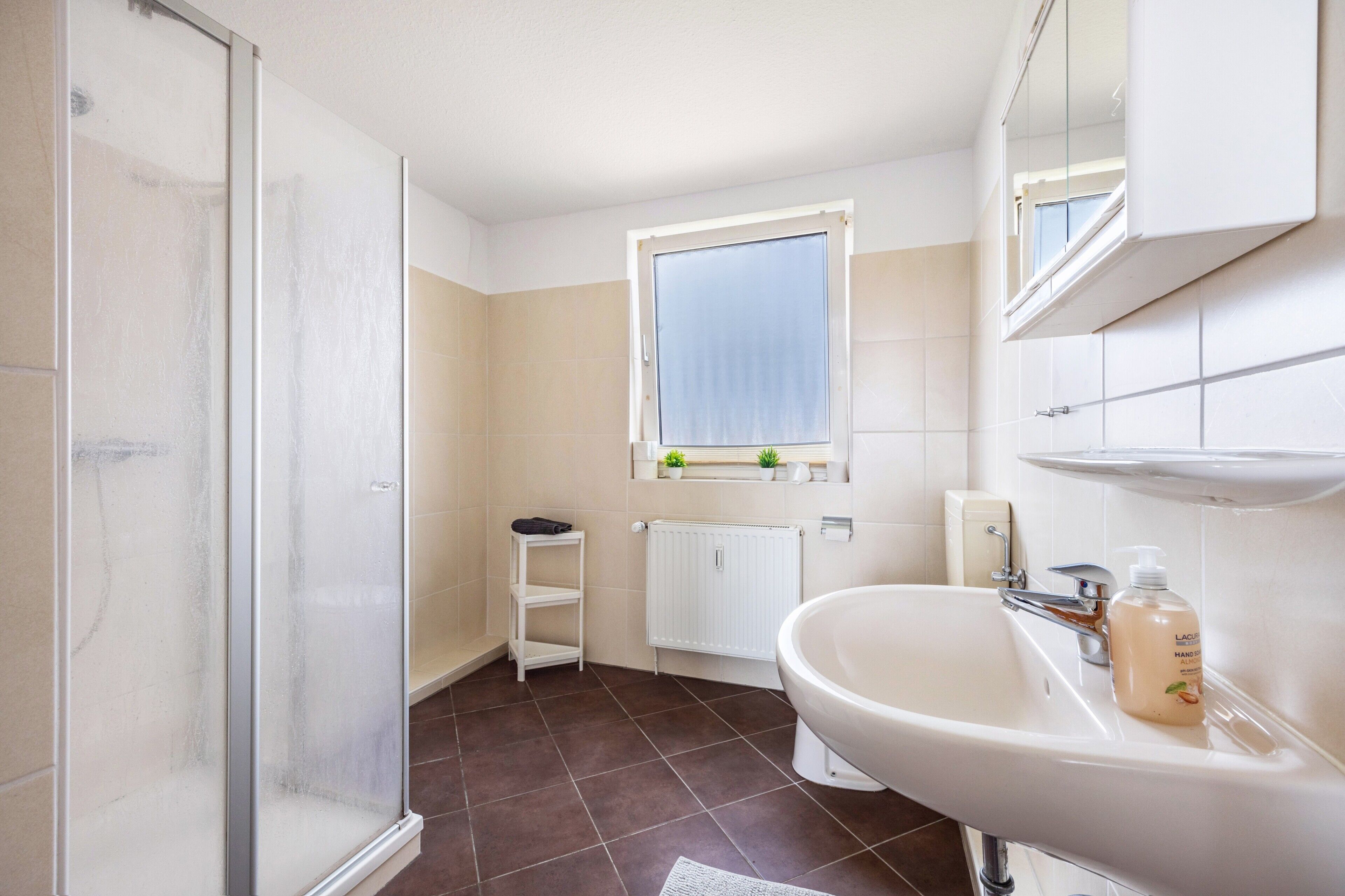 Ein Badezimmer mit Dusche, Waschbecken und Fenster.