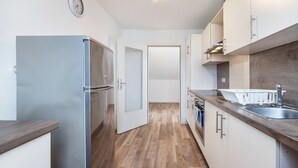 Una cocina moderna con refrigerador de acero inoxidable, suelo de madera y armarios blancos.