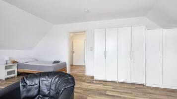 A bedroom with a bed, a chair, a wardrobe, and a nightstand.