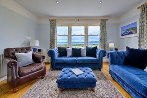 Ein Wohnzimmer mit einem braunen Ledersessel, einem blauen Sofa und einem passenden Hocker.