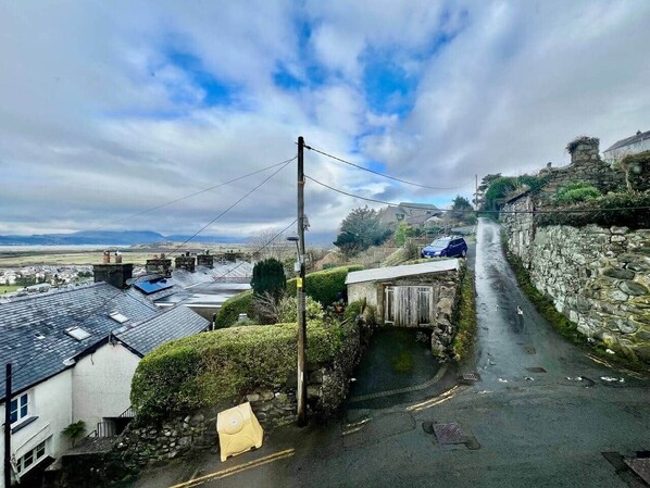 A narrow road with stone walls on one side and buildings on the other.