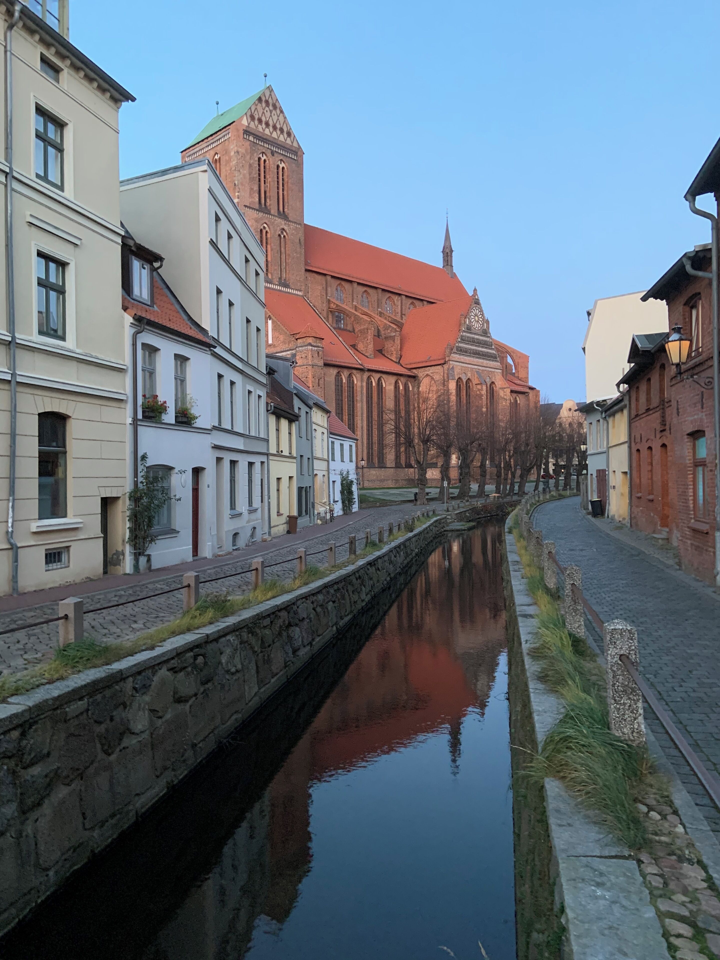 Ein Kanal, an dessen Ufern Gebäude stehen, darunter eine Kirche mit rotem Dach.