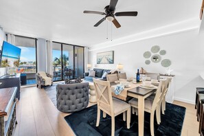 Una sala de estar moderna con comedor, un ventilador de techo y un ventanal con vistas.