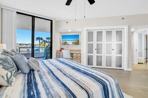 Un dormitorio con cama, escritorio, silla, armario y vista al mar.
