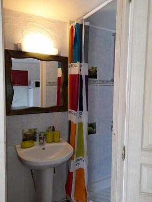 A bathroom with a white sink, a mirror, and a shower curtain with colorful stripes. - Holiday Village (Reclinghem)