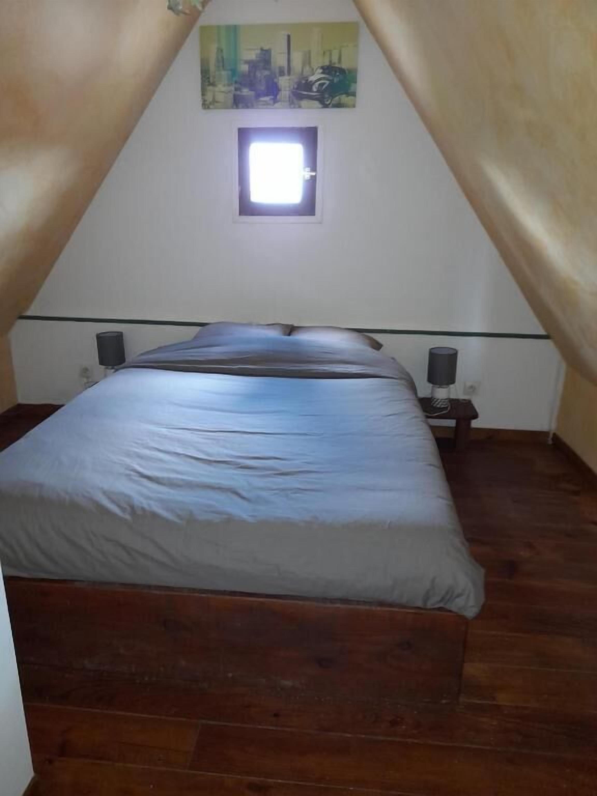 A bedroom with a single bed, a small window, and two bedside tables with lamps.