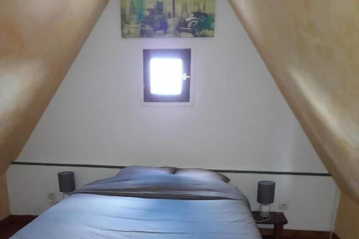 A bedroom with a single bed, a small window, and two bedside tables with lamps.
