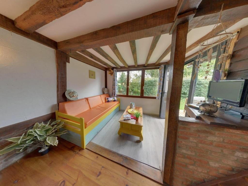 A cozy room with a wooden ceiling, a sofa, a small table, and a television.