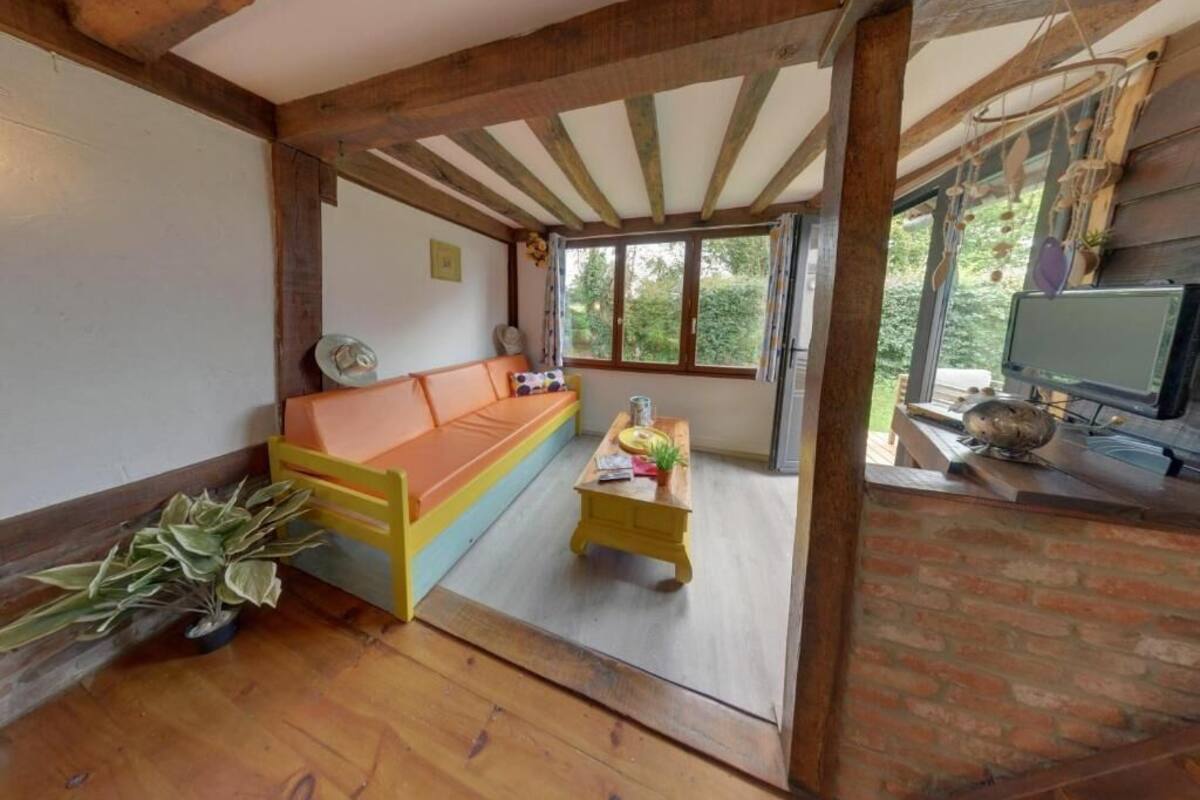Una habitación acogedora con techo de madera, un sofá, una mesita y un televisor.
