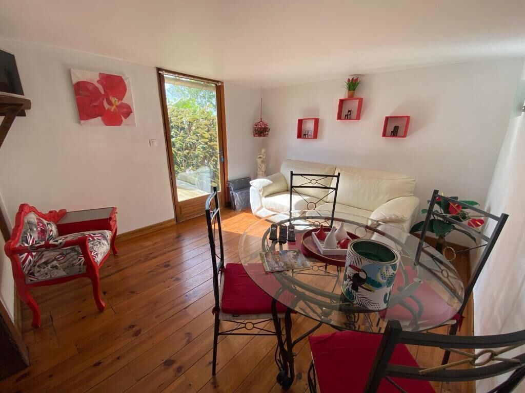 A room with a glass table, red chairs, a white sofa, and a red bench.