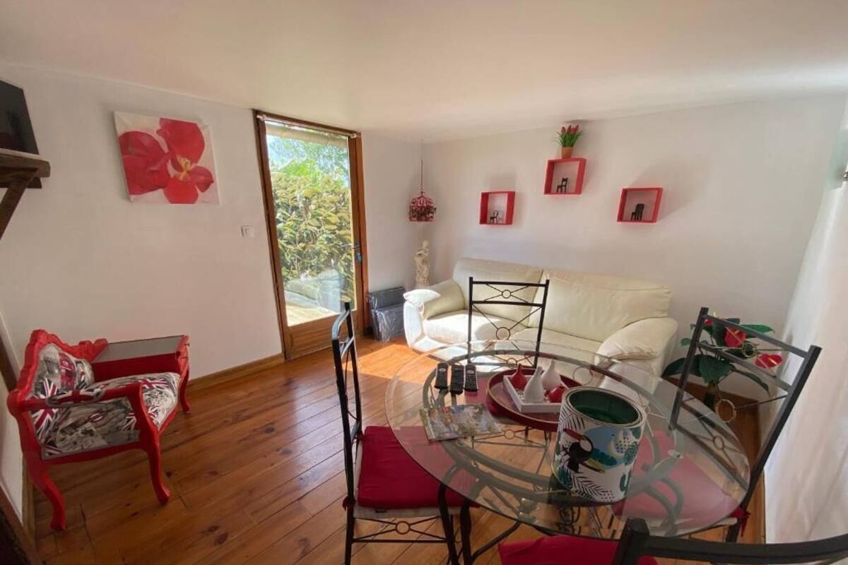 Una habitación con una mesa de vidrio, sillas rojas, un sofá blanco y un banco rojo.