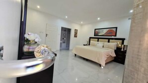 A bedroom with a bed, a nightstand, a door, and a painting on the wall. - The View Luxury Guest House (Chinhoyi)