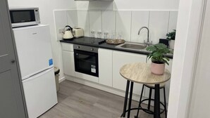 Eine kleine Küche mit Mikrowelle, Toaster, Spüle und einem Essbereich mit Hockern.
