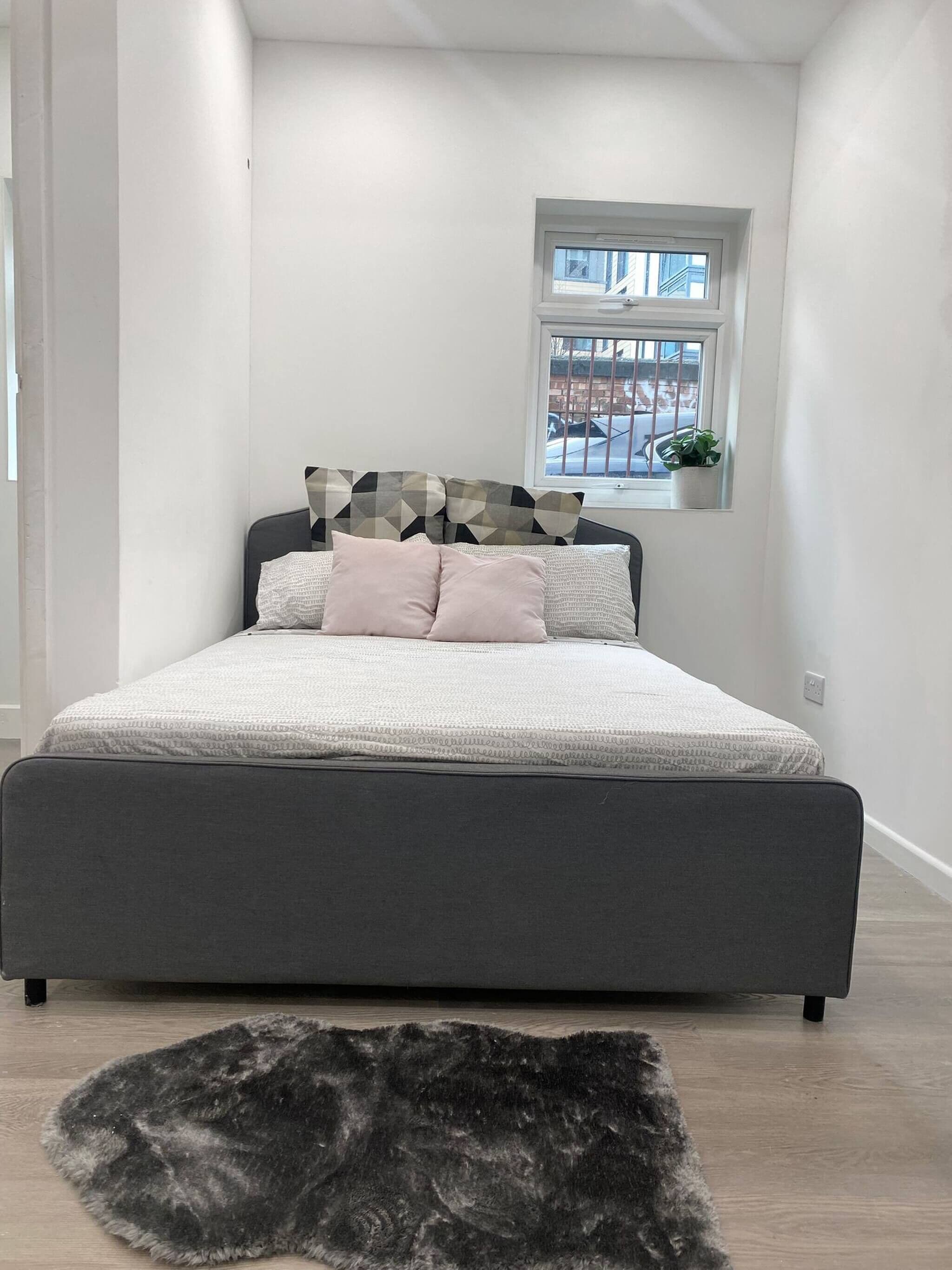 Un dormitorio moderno con una cama grande, una ventana que ofrece vistas al exterior y una planta pequeña en el alf éizar.