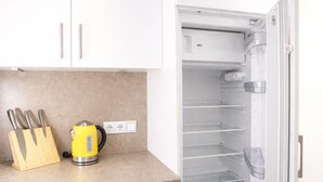 A kitchen with white cabinets, a countertop, a kettle, and a refrigerator. - Dengg down town studios Apartment (Innsbruck)