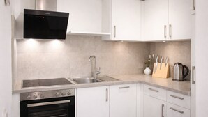 A modern kitchen with white cabinets, stainless steel appliances, and a built-in oven. - Dengg down town studios Apartment (Innsbruck)