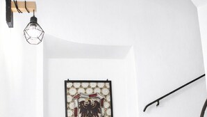 Una scala con gradini in legno, un lampadario a parete e un emblema incorniciato al muro.