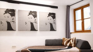 Una stanza con un divano grigio, una coperta decorata e tre quadri in bianco e nero appesi al muro.