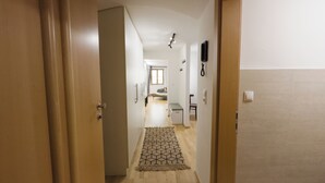 Un corridoio con porte in legno, un tappeto decorato e un muro piastrellato.