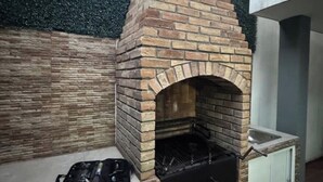 A brick-built outdoor fireplace with a chimney, a small sink, and a black grill.