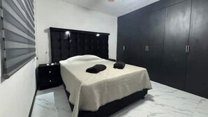 A bedroom with a bed, dark wardrobe, and a ceiling fan.