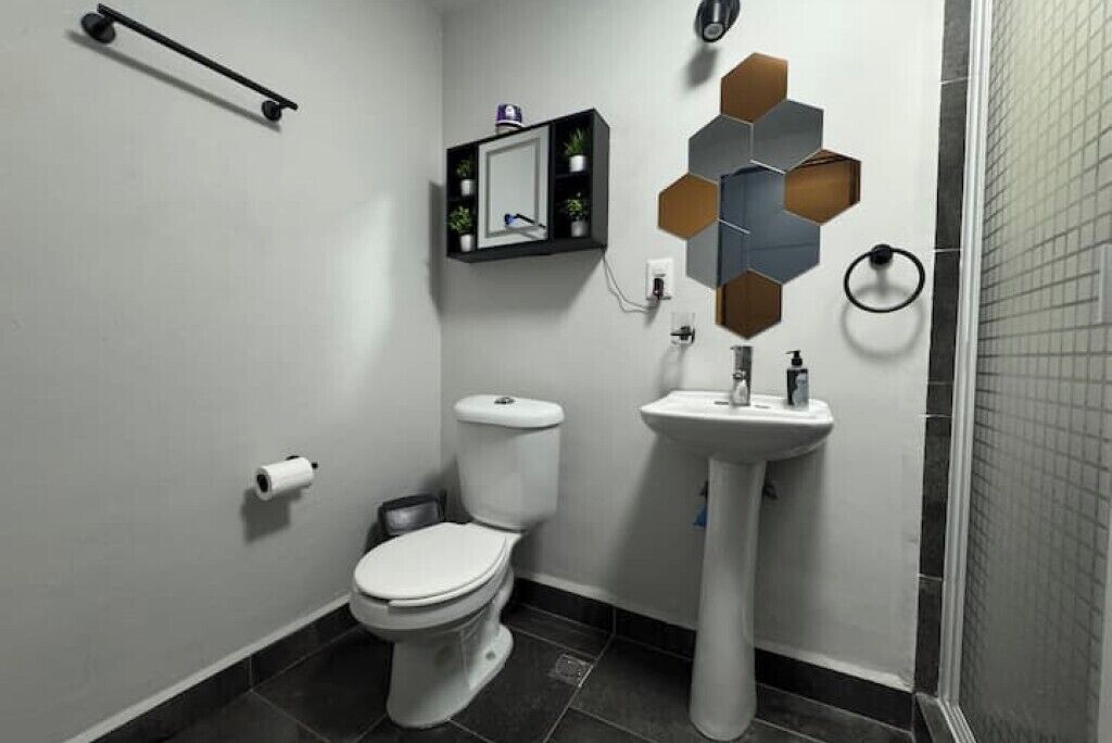 A modern bathroom with a toilet, sink, and mirror.