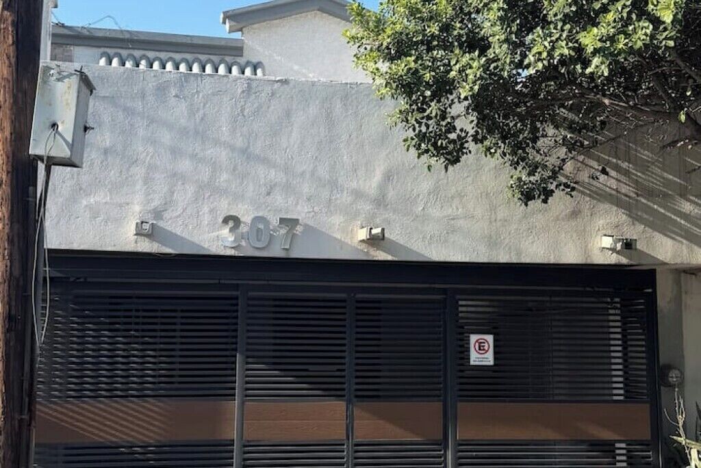 A building with the number 307 on its facade, a closed shutter door, and a no parking sign.