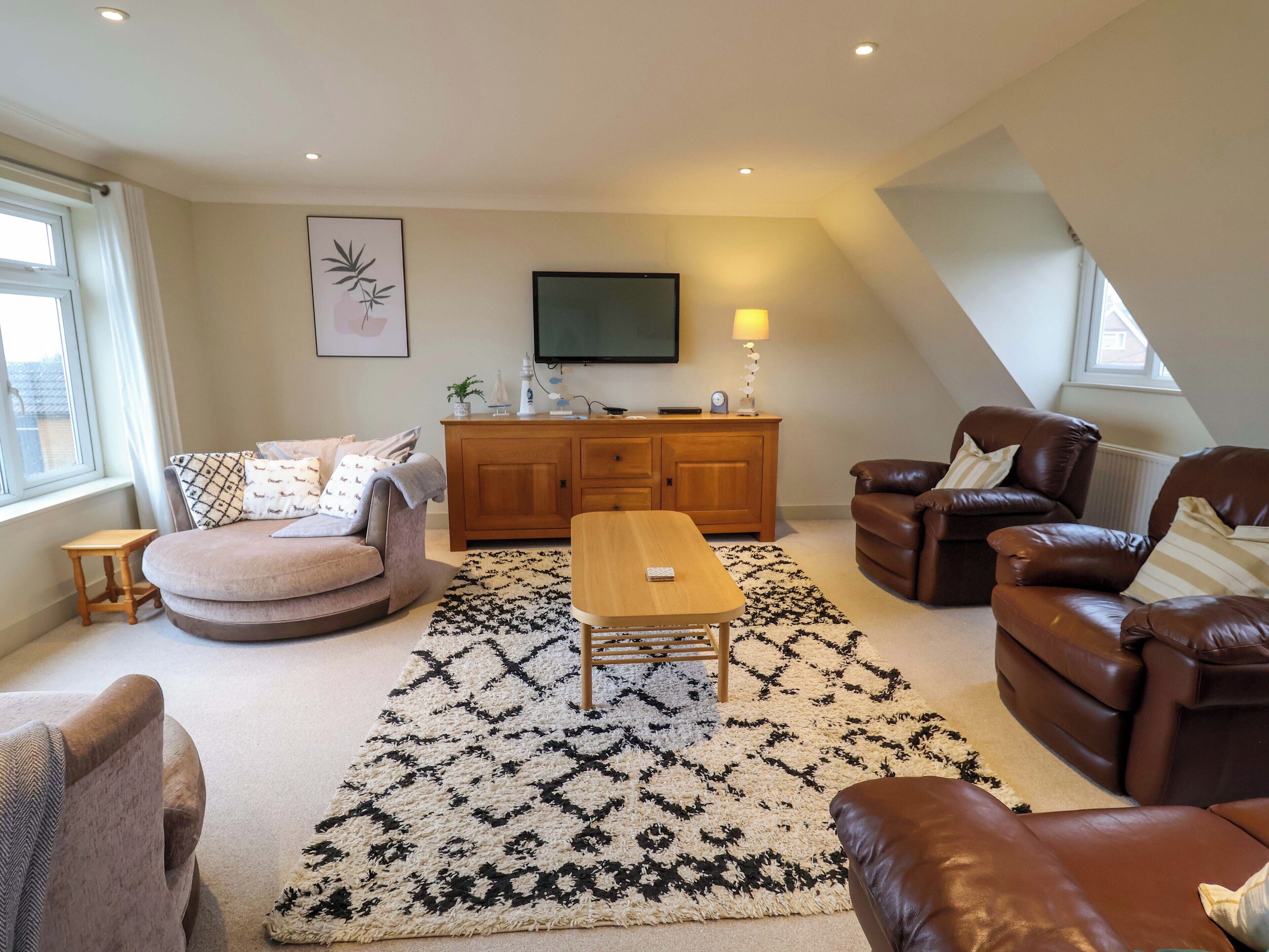A living room with a sofa, armchairs, a coffee table, a TV, and a cabinet.