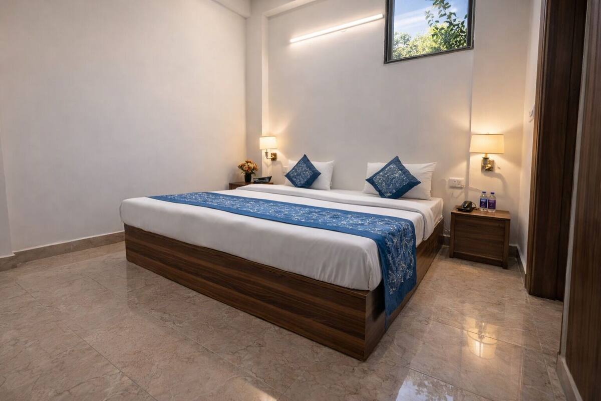 Ein Hotelzimmer mit einem großen Bett, zwei Nachttischen, einer Wandlampe und einem kleinen Tischchen.