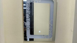 A bathroom with a white sink, a mirror with a decorative frame, and a dark wooden vanity. - Hotel Rashmi Grand (Khagaria)