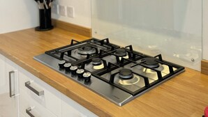 A modern kitchen with a stainless steel gas stove, a black range hood, and a wooden countertop. - The Ravens Inn, 4 - Bed, Sleeps 6, Long Term Rental Available (Ulverston)