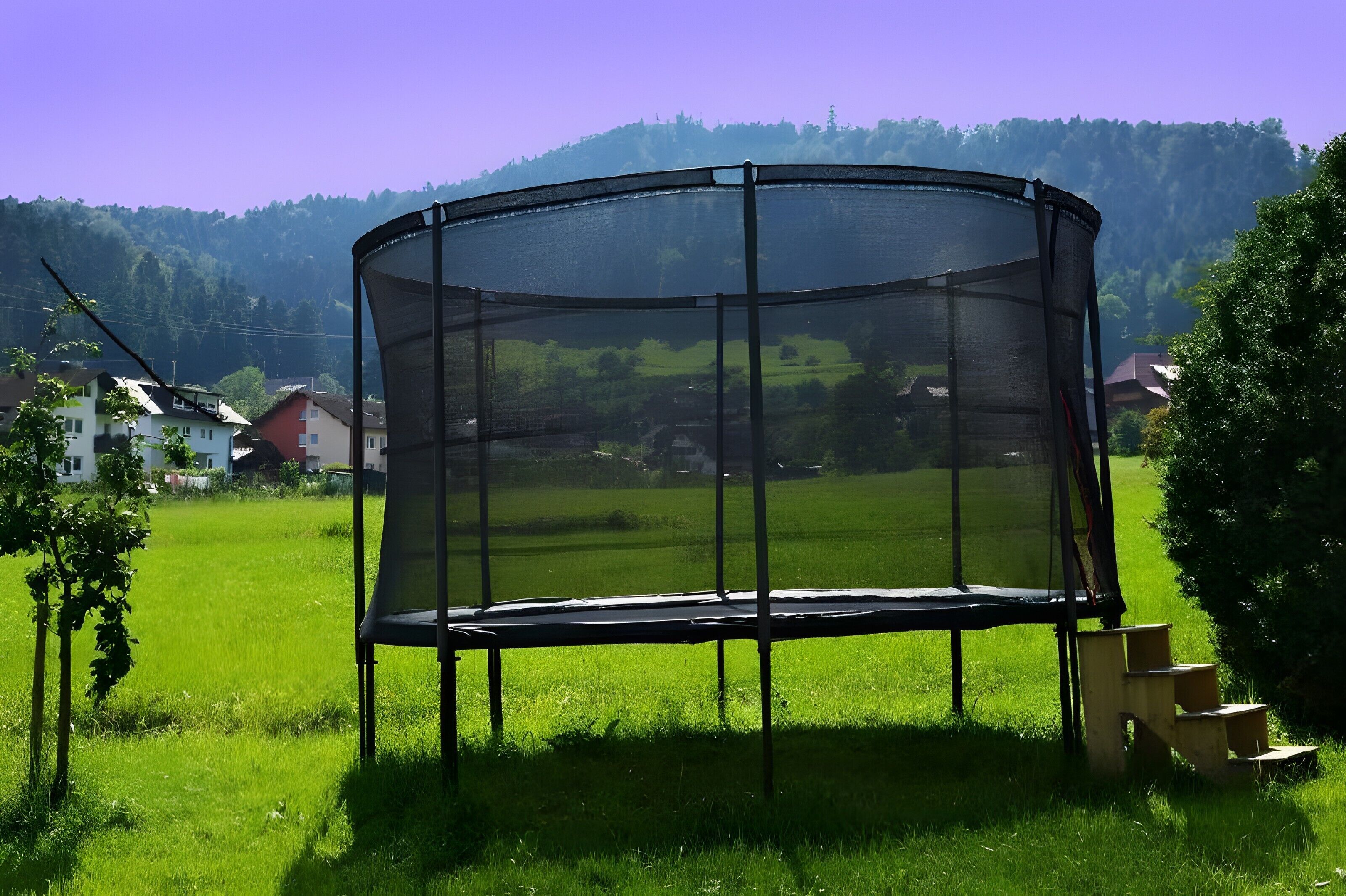 Un trampolín en un campo cubierto de hierba, con casas al fondo.