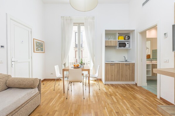A compact living space with a dining area, kitchenette, and a sofa.