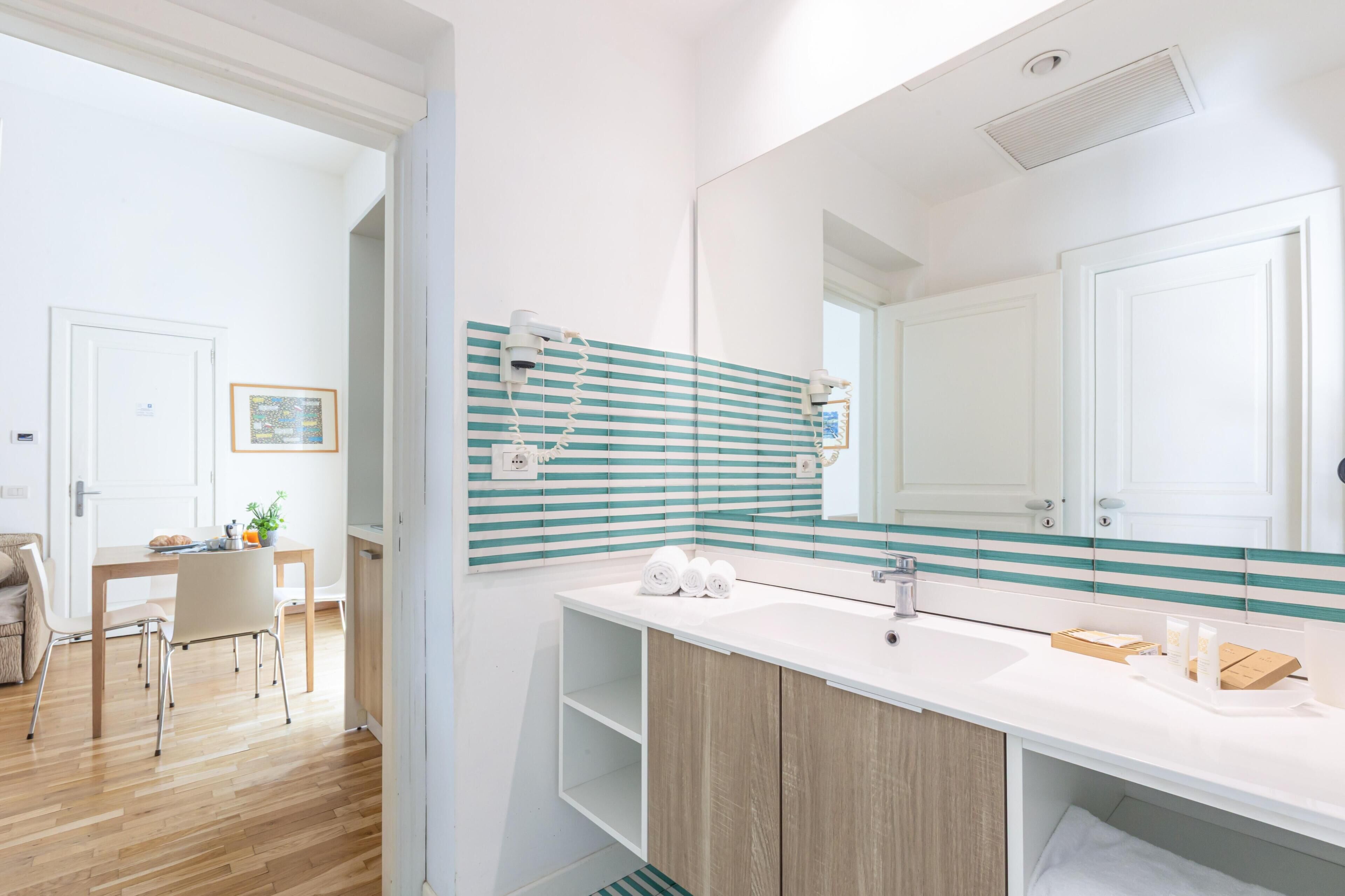 A modern bathroom with a large mirror, wooden vanity, and a striped backsplash.