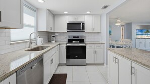 A modern kitchen with white cabinetry, stainless steel appliances, and a granite countertop. - Villa 13 Island House (Sarasota)