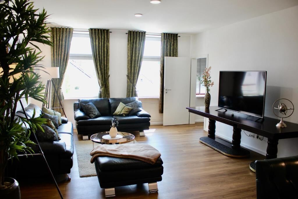 A modern living room with a black sofa, a coffee table, and a TV on a stand.