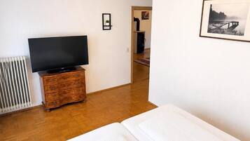 A room with a bed, a dresser, a television, and a framed picture on the wall.